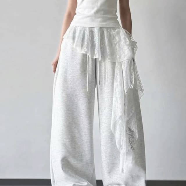 Falda corta con volantes y ribetes de encaje, diseño floral bordado, dobladillo irregular, cintura alta, fruncida, estilo minifalda tipo delantal para superposición.